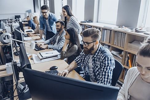 A group of people working on computers in an office setting